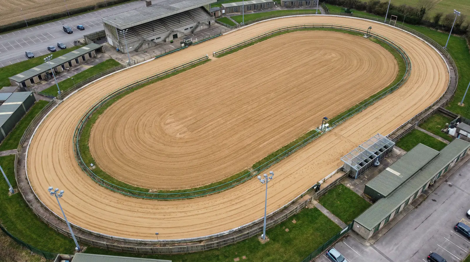 Aerial view of a GBGB-registered greyhound racing track showing the oval sand circuit with tight bends